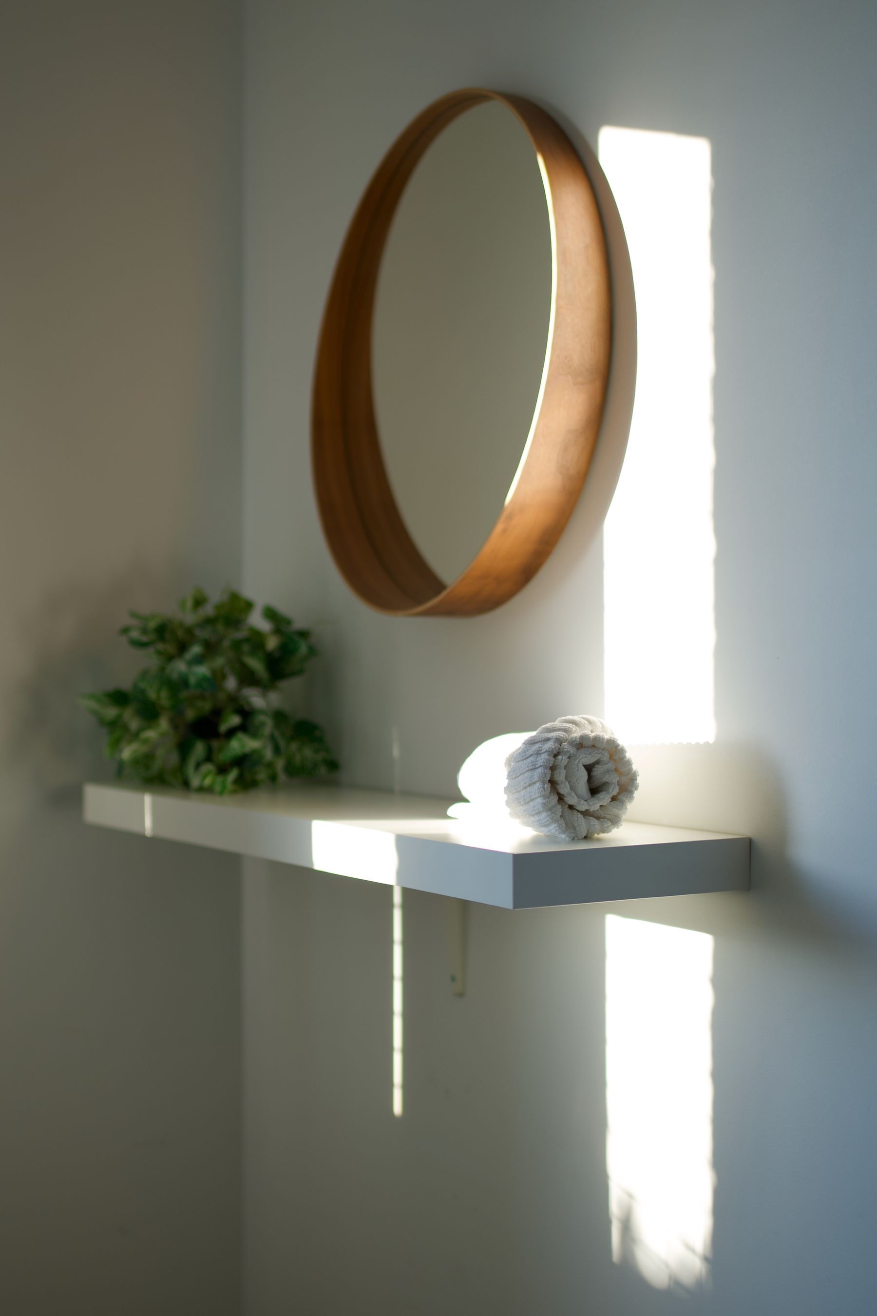 Round mirror and shelf catching afternoon light